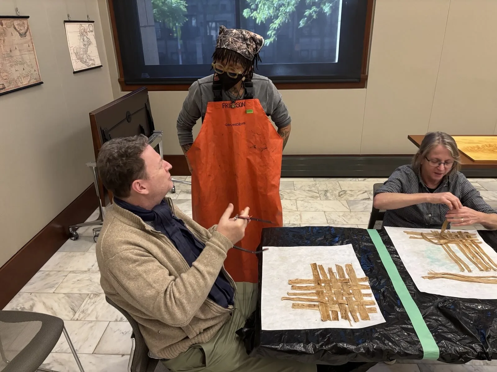 Instructor discusses paper making with particpant. Participant arranges fibers.